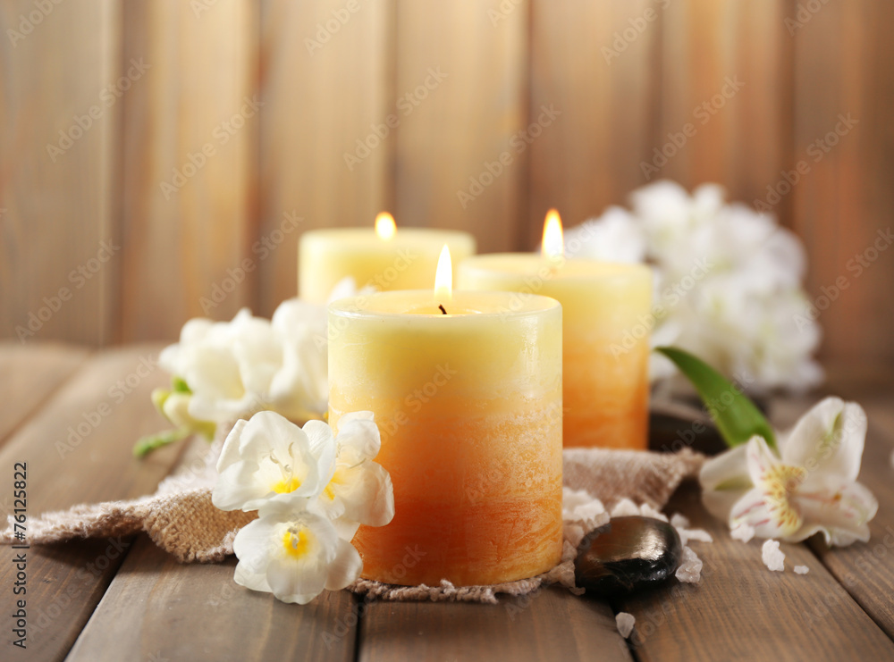 Beautiful candles with flowers on wooden background