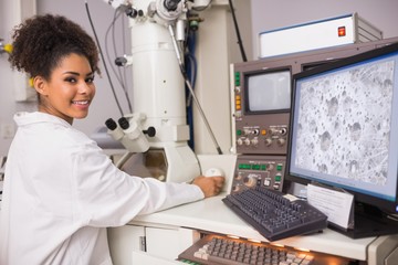 Wall Mural - biochemistry student using large microscope and computer