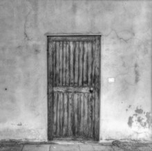 Old Wooden Door In A Grunge Wall In Black And White
