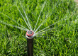 Automatic sprinkler spraying water onto green grass