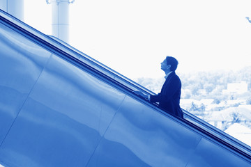 Indian businessman ascending escalator