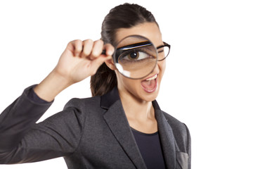 happy young woman looking through a magnifying glass