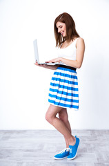 Wall Mural - Portrait of a smiling woman standing and using laptop