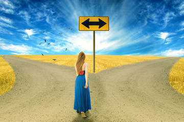 Young woman standing in front of two roads arrow sign 