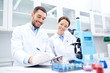 © Syda Productions - scientists with clipboard and microscope in lab