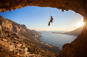 Wall Mural - Rock climber hanging on rope while lead climbing before sunset