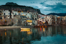 Old Boat And Houses In Cefalu At Dusk