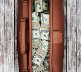 Wall Mural - suitcase full of dollars on a wooden background. view from above