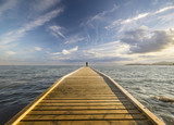 Fototapeta Pomosty - Wędkarz łowiący w morzu z drewnianego pomostu