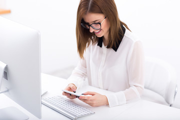 Canvas Print - Happy businesswoman using smartphone at her workplace in office