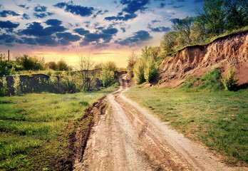 Wall Mural - dirt road passing by earthen cliff to the sun
