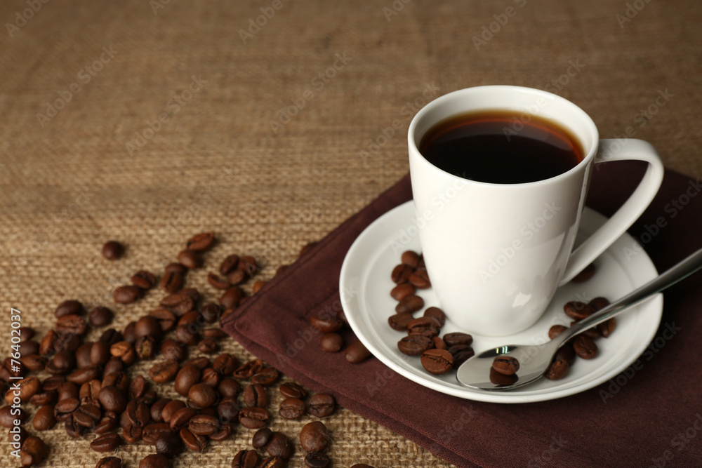 Cup of coffee with beans on rustic wooden background