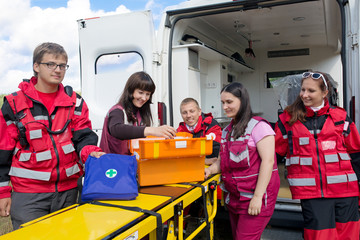 Group paramedics with medicine chest on ambulance background