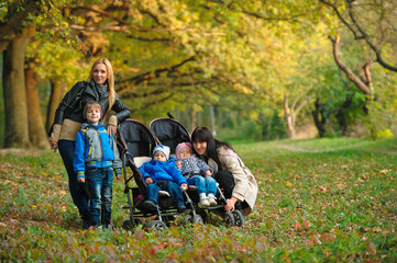 Wall Mural - mothers with children twins on a walk in the autumn park