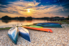 Parked Canoes By The Lake At Sunset