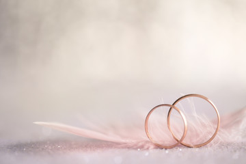 Two Golden Wedding Rings and  Feather - gentle background