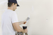 © pfluegler photo - Mann spachtelt Risse an Wand