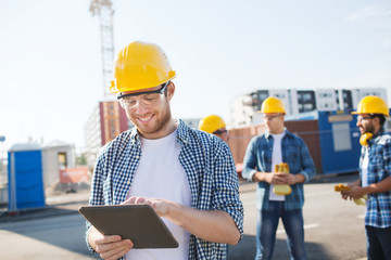 smiling builders in hardhats with tablet pc