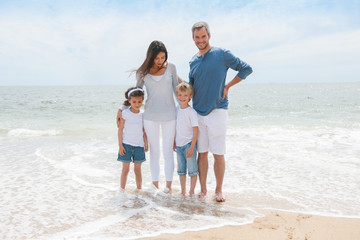 Wall Mural - A happy family is facing the camera in front of the beac