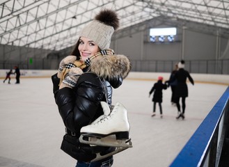 Wall Mural - Cheerful girl with skates on ice skating rink