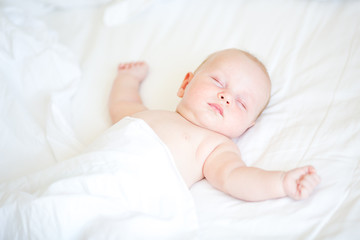 peaceful newborn baby lying on a bed sleeping