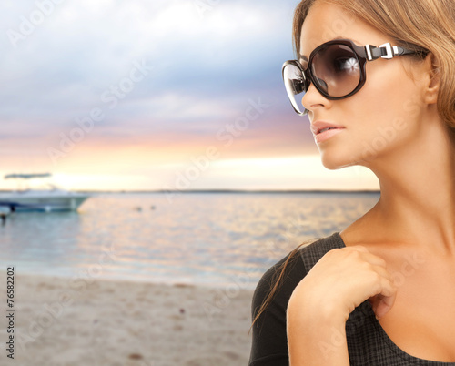 Fototapeta na wymiar young woman in shades over sea shore background