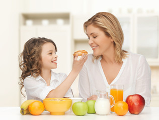 Canvas Print - happy mother and daughter eating breakfast