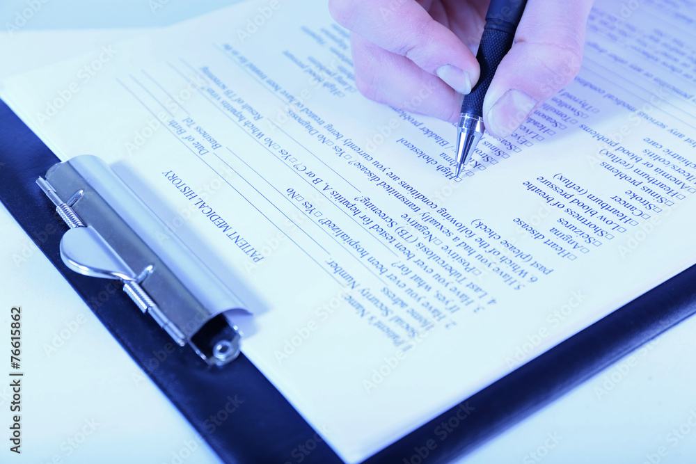 Woman filling medical history on light background