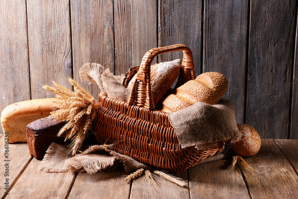 Different bread in wicker basket on table on wooden background