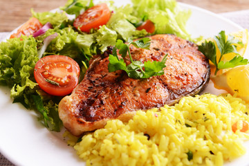 Tasty baked fish with rice on plate on table close-up