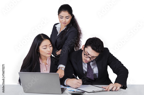 Foto Geschäftsteam, das an Schreibtisch mit Laptop arbeitet