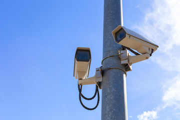 two cctv on metal light pole watching the car parking yard