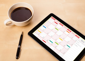 Wall Mural - tablet pc showing calendar on screen with a cup of coffee on a d
