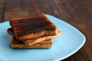 Poster - Burnt toast bread on turquoise plate, on wooden table