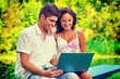 © mihalec - young couple sitting holding laptop looking on it and smiling in