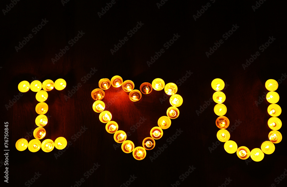 Words I LOVE YOU formed by burning candles on dark background