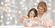 © Syda Productions - mother and daughter putting money to piggy banks