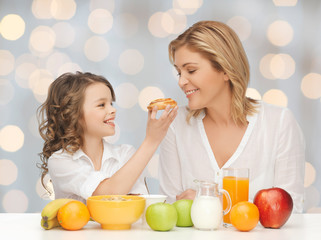 Wall Mural - happy mother and daughter eating breakfast