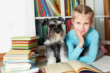 girl and her dog in glasses reading a book, sitting on floor in