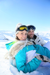 Wall Mural - Couple of skiers sitting in snow at top of mountain