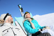 © goodluz - Couple of skiers sunbathing at top of ski slope