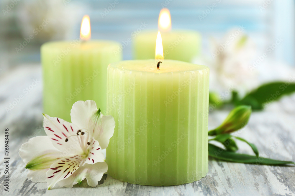 Beautiful candles with flowers on wooden background