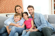 © goodluz - Cheerful family at home sitting in sofa