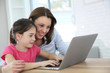 © goodluz - Woman with girl doing homework on laptop