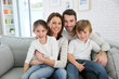 © goodluz - Cheerful family at home sitting in sofa