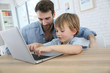 © goodluz - Daddy and son playing on laptop computer