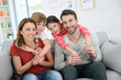 © goodluz - Cheerful family at home sitting in sofa