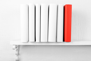 Canvas Print - Blank books with red one on bookshelf on white wall background