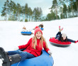 © Syda Productions - group of happy friends sliding down on snow tubes