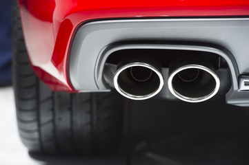 Chrome exhaust pipe of red powerful sport car bumper